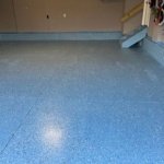 Garage floor transformed with a decorative epoxy coating featuring blue and gray flakes.